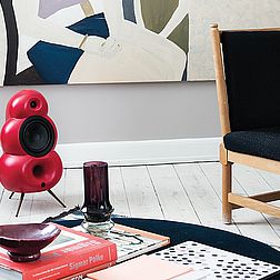 ein roter Podspeaker Bigpod steht auf dem Fußboden zwischen zwei Sofas