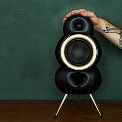 ein schwarzer Podspeaker mit messingfarbenem Chassisring